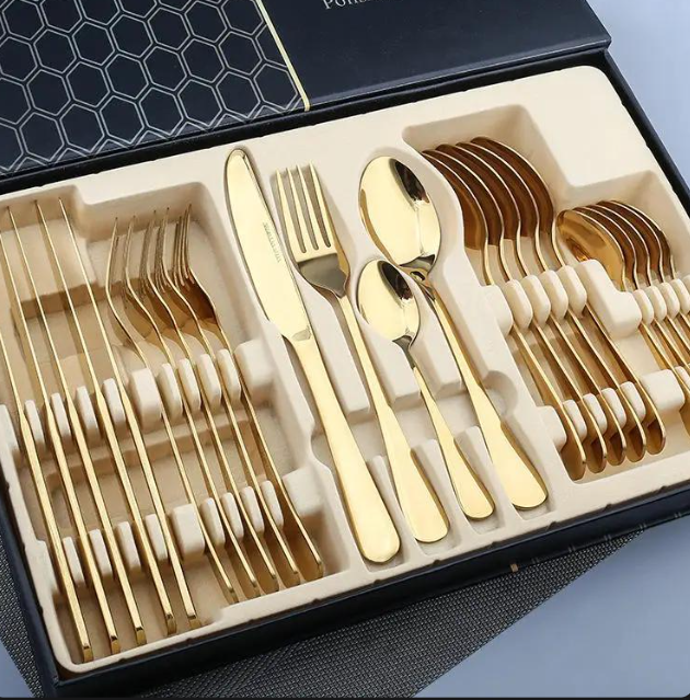 Close-up of gold-tone stainless steel cutlery arranged inside a black gift box